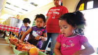 La maestra pre-escolar Charlotte Pinkney ayuda a sus estudiantes a escoger hortalizas del mercado “Healthy Children, Healthy Lives”, el 24 de abril. Preschool teacher Charlotte Pinkney helps her students pick produce from the “Healthy Children, Healthy Lives” Farmer’s Market on April 24.  Photo Ramsey El-Qare